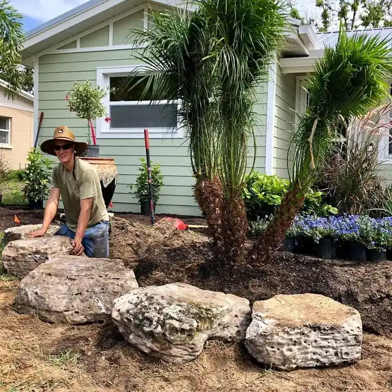 A Master’s Touch crew member setting limestone boulders beside a newly planted palm
